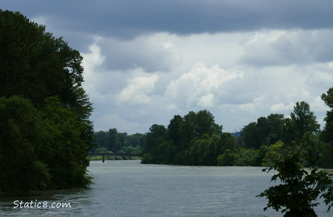 Moody clouds over the river with a bridge in the distance