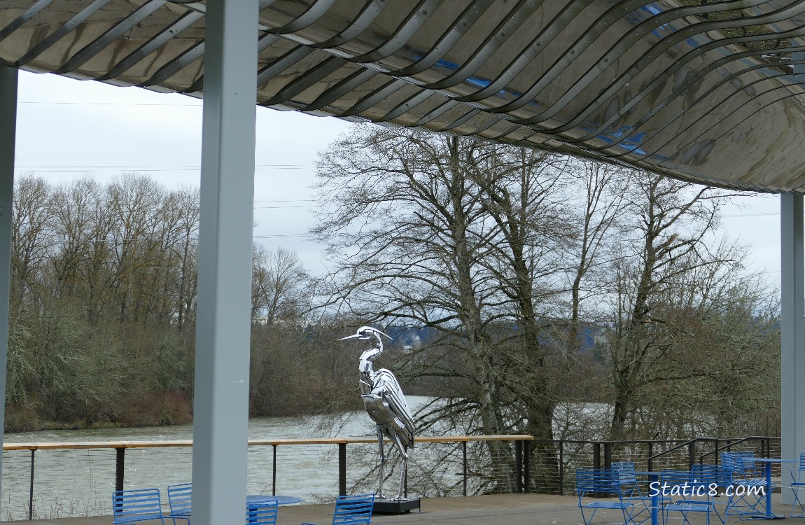 Looking past a chrome Heron statue to the river