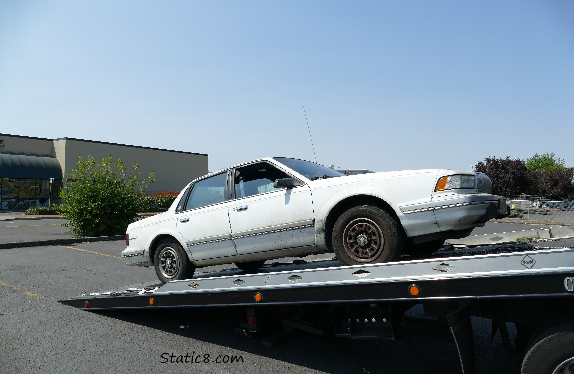 White car coming off a tow truck