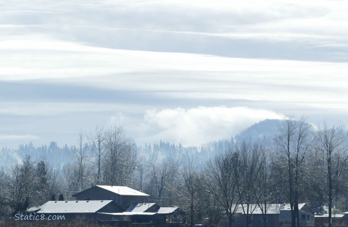 multiple layers of grey and white clouds over the hill in the distance