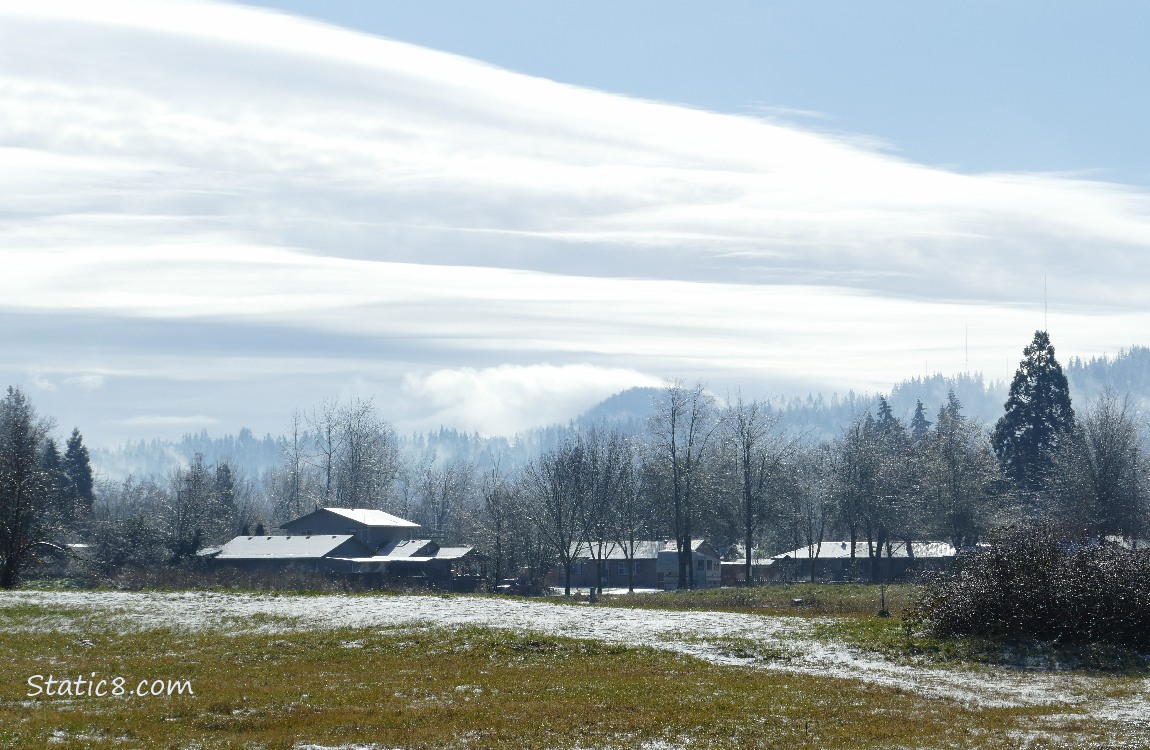 Long clouds and blue sky over the hill in the distance