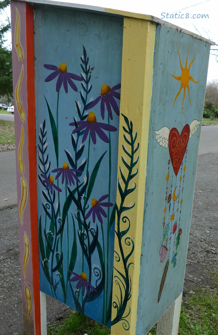 The back of a Little Free Pantry with flowers painted on it