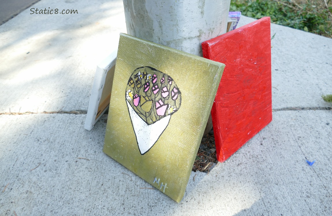 Flowers painted on a canvas leaning against a light pole