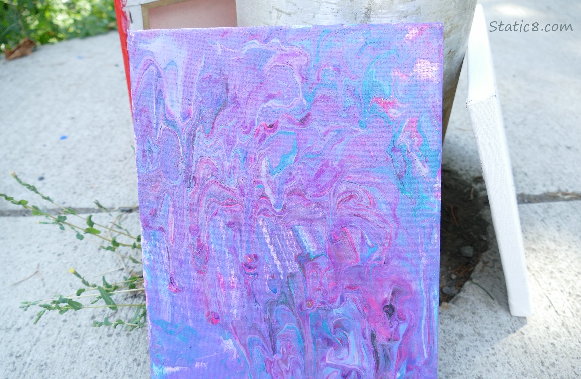 Purple and blue marbling painted on a canvas, leaning against a light pole