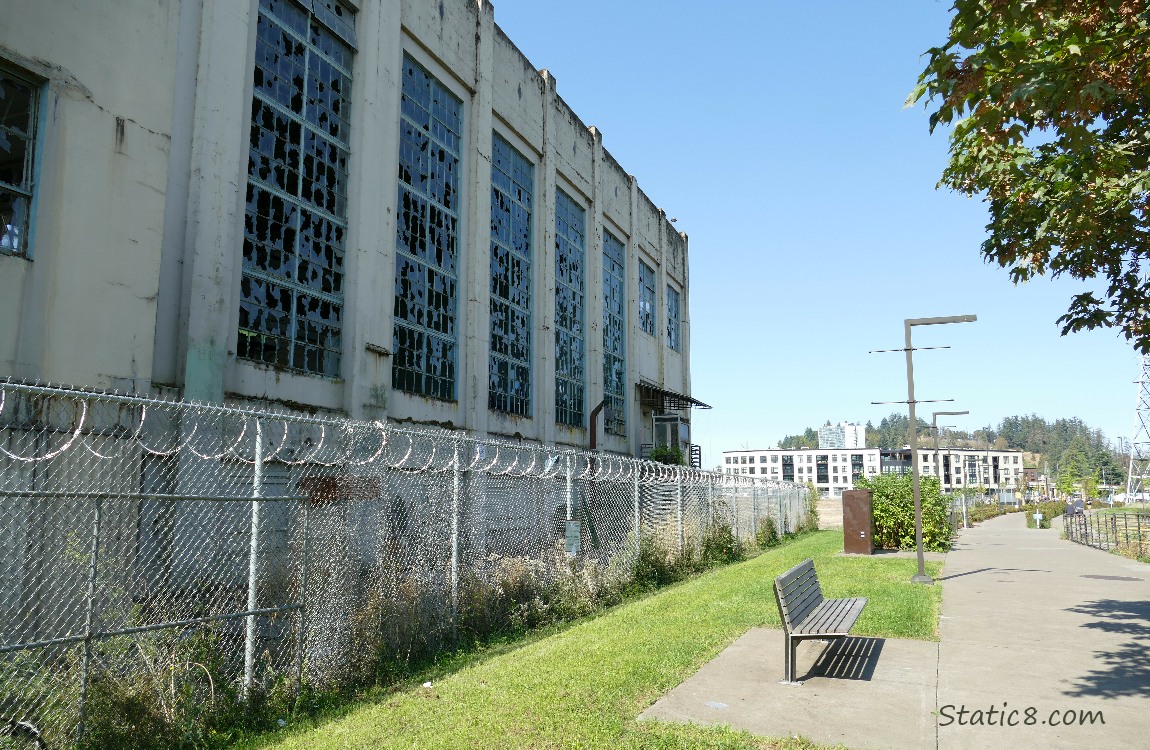 Building next to the bike path, behind a chain link fence and  with broken windows 