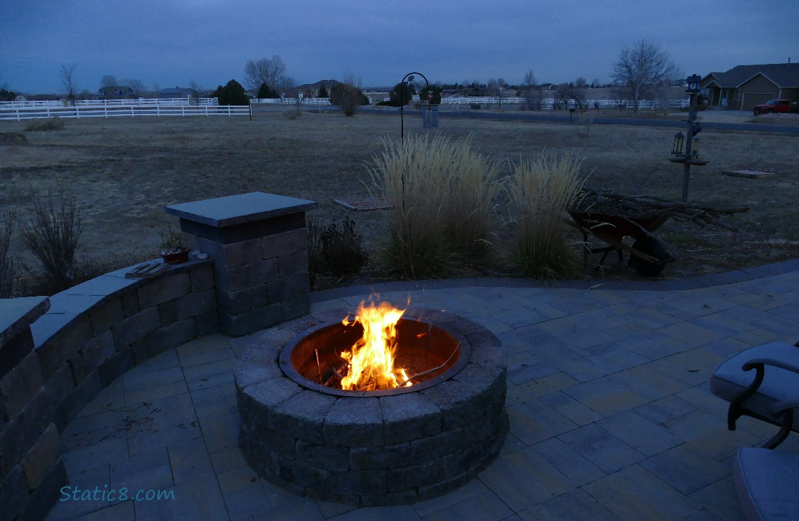 Lit fire pit with the darkening yard beyond