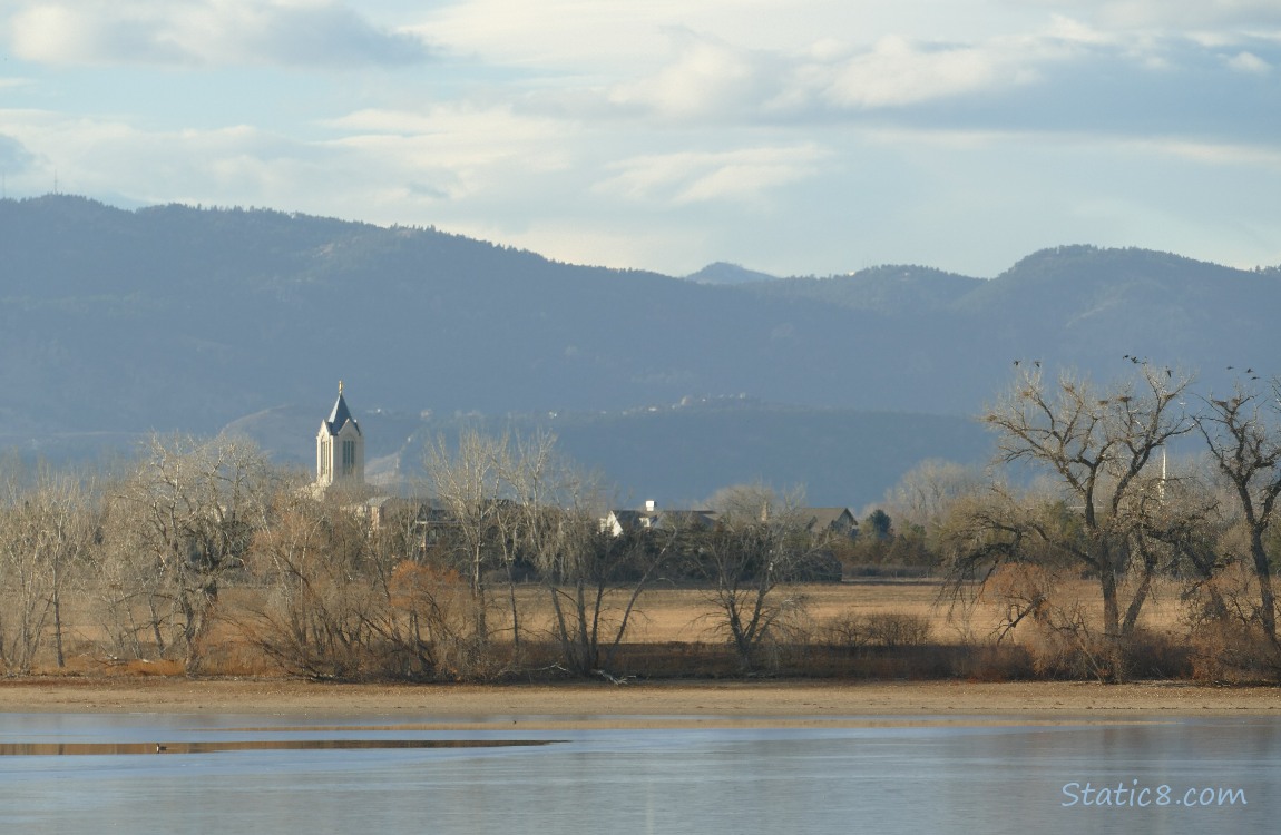 View across the lake of a church steeple with hills in the background