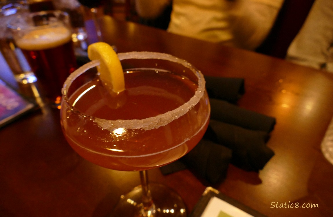 Martini on a table with a glass of beer and wrapped silverware