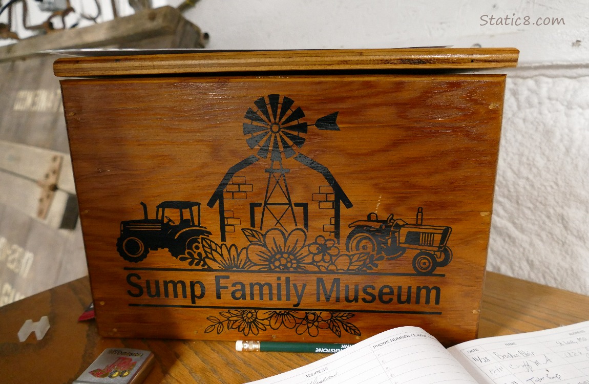 Wood sign that says Sump Family Museum with decorative tractors, a barn and flowers etched into the wood