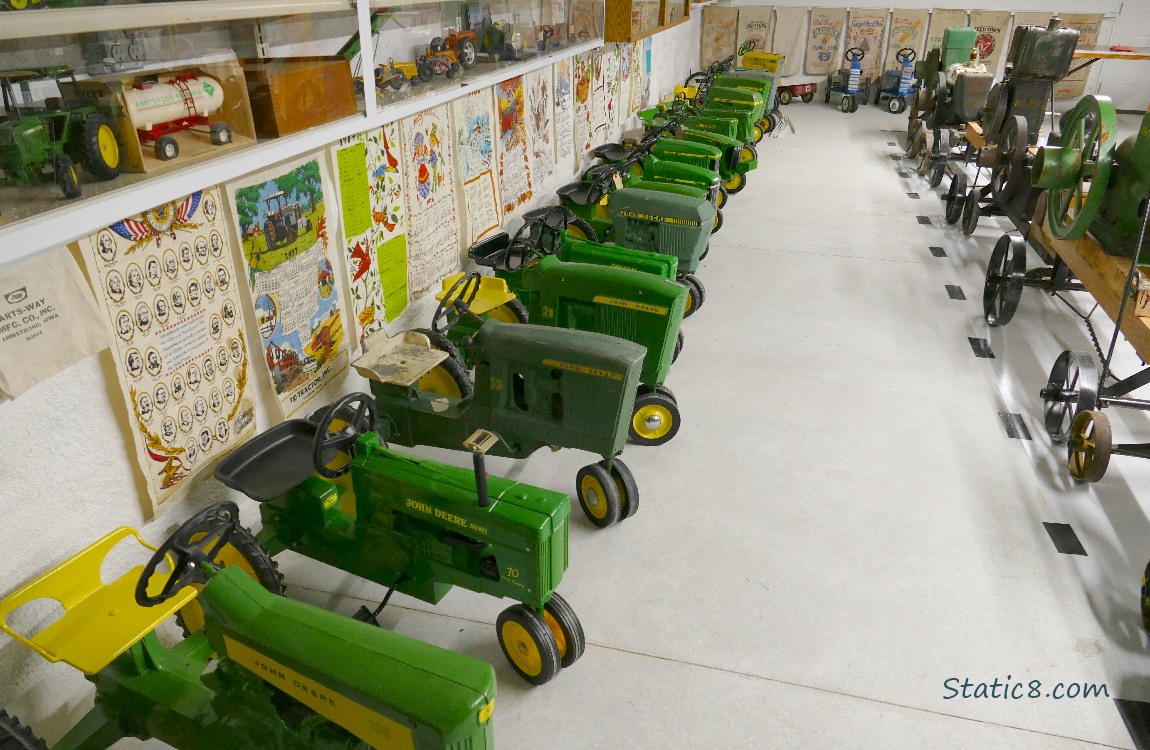 Toy John Deere tractors lined up along a wall