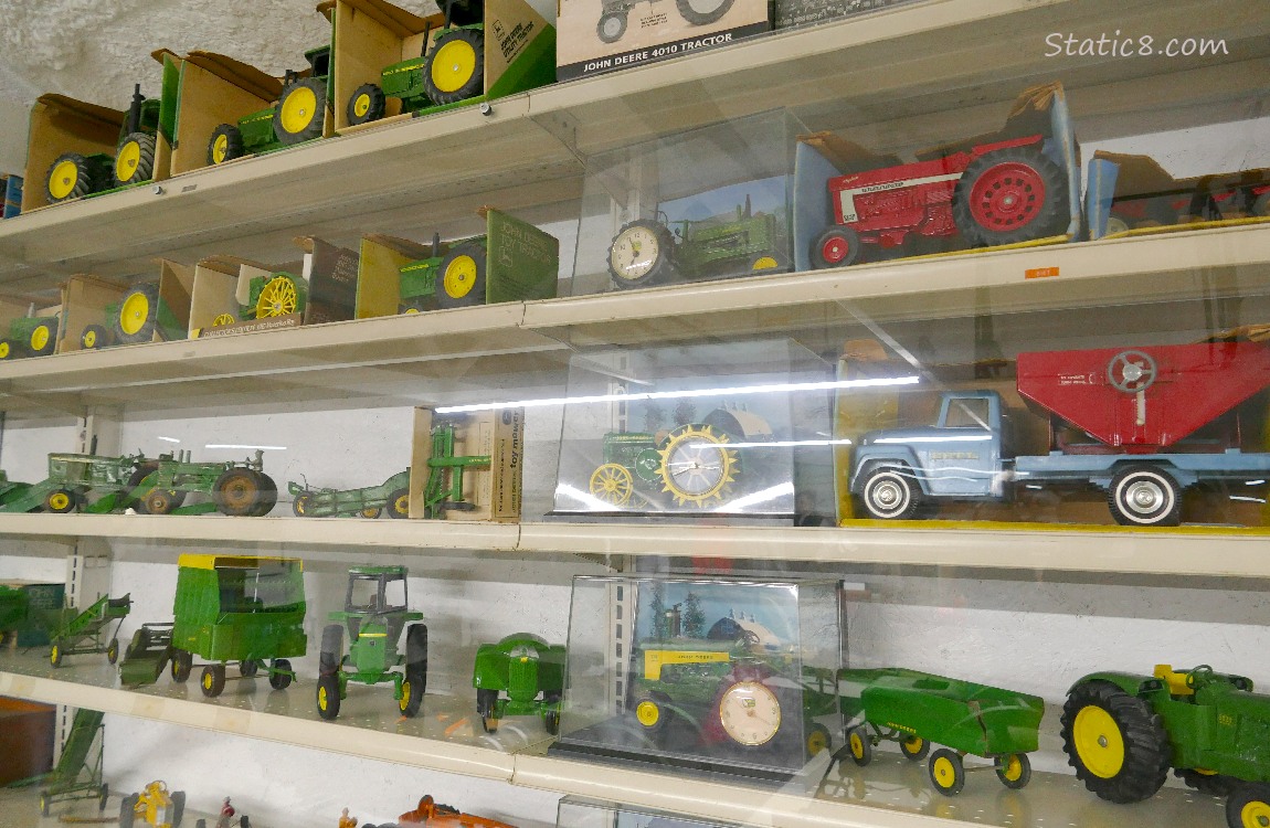 Collectable toy John Deer tractors on a shelf, some in their original packaging