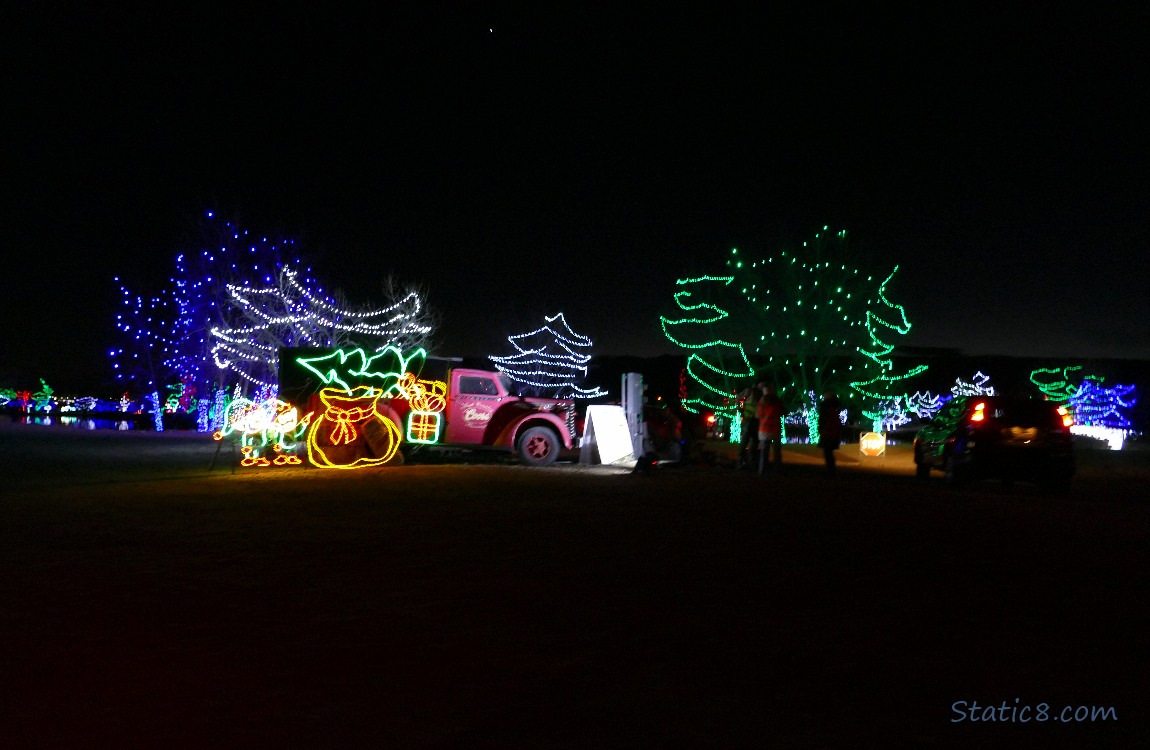 Lit pickup truck with a lit christmas tree and bag of gifts