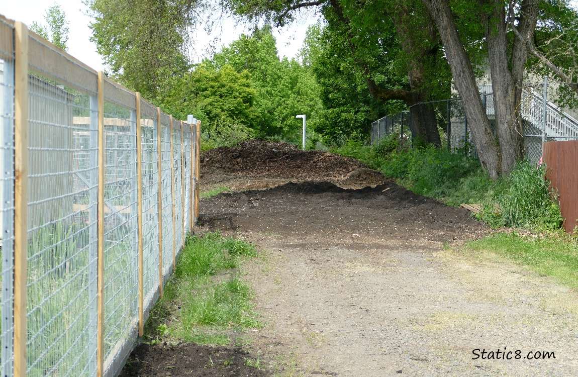 Pile of dirt next to the garden fence