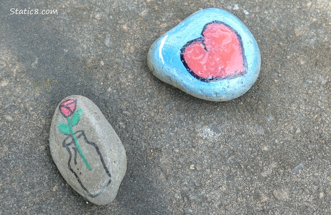 Painted rocks of a heart and a cut rose in a vase