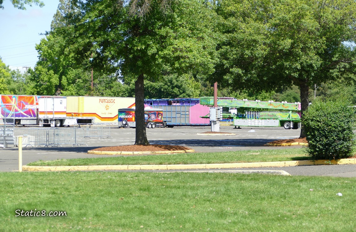 Colourful semi-truck trailers in a parking lot past green trees