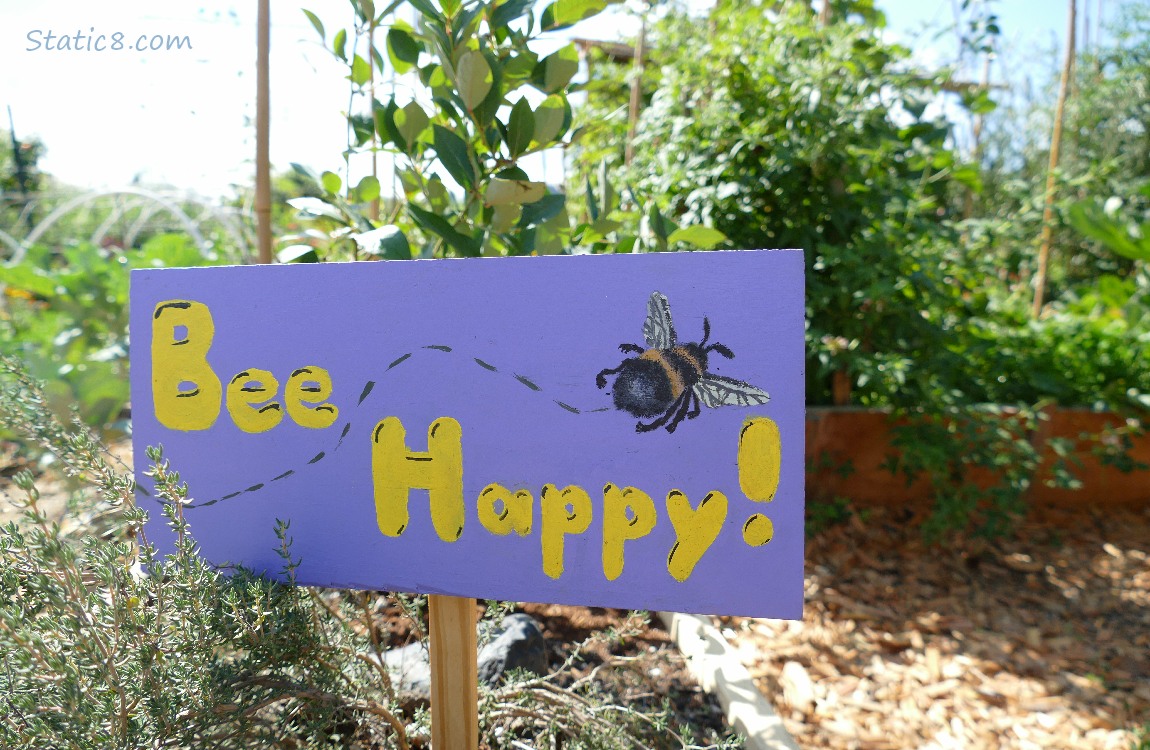 Garden sign that says Bee Happy with the drawing of a Bumblebee flying away